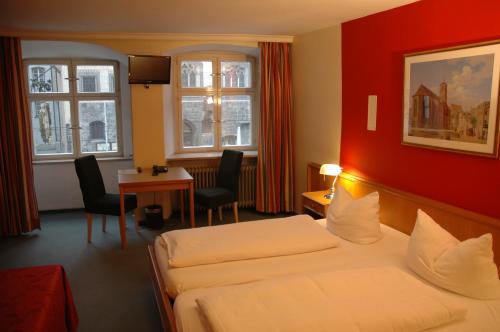 a hotel room with two beds and a table and chairs at Hotel Paulanerstuben in Wasserburg am Inn