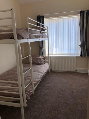 a bedroom with two bunk beds and a window at Bea's Cottage in Newbiggin-by-the-Sea