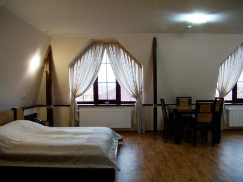 a bedroom with a bed and a table and windows at Hotel Zolota Pidkova in Kozlin