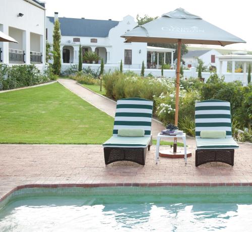 zwei Stühle und ein Sonnenschirm neben einem Pool in der Unterkunft Val Du Charron Wine & Leisure Estate in Wellington