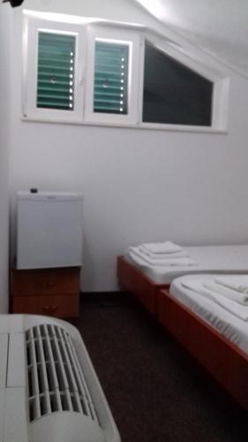 two beds in a room with two windows at Guest House Babić in Neum