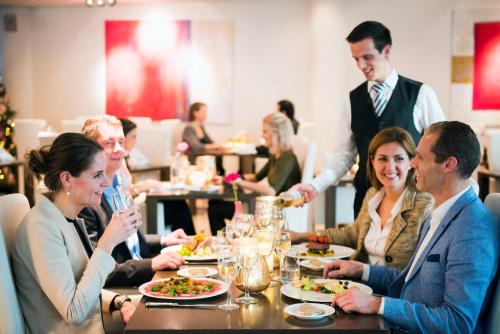 a group of people sitting around a table in a restaurant at Sanadome Hotel & Spa Nijmegen in Nijmegen