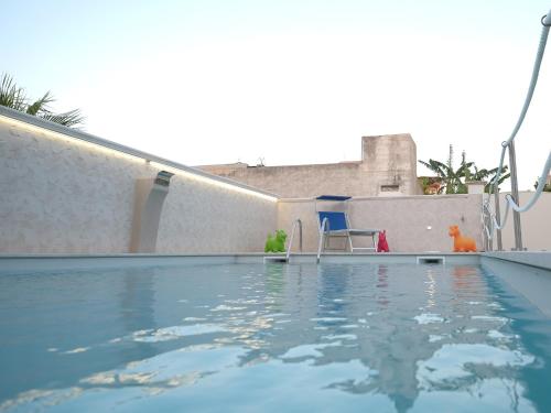 マツァーラ・デル・ヴァッロにあるMorgana Villaの壁の隣に青い椅子が備わるスイミングプール