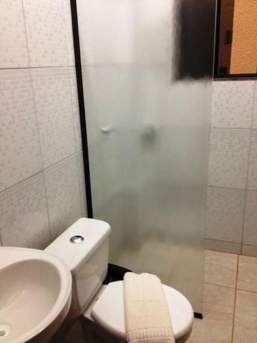 a bathroom with a shower and a toilet and a sink at Hotel Sarandi in Foz do Iguaçu