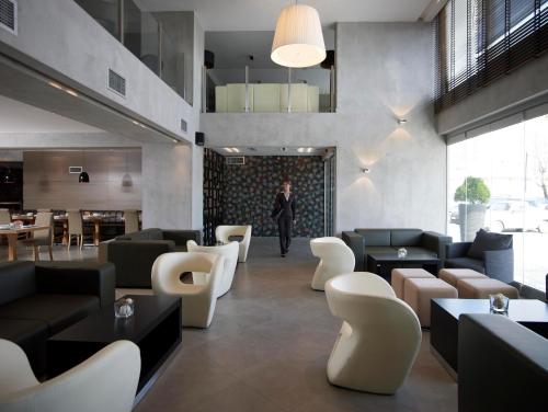 a woman walking through a lobby with couches and chairs at Anatolia Hotel Komotini in Komotini