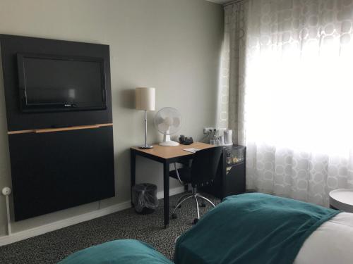 a bedroom with a desk with a tv and a bed at Glostrup Park Hotel in Glostrup