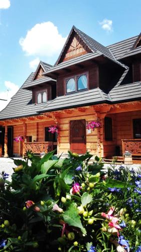 a wooden house with flowers in front of it at U Dziadka in Chochołów