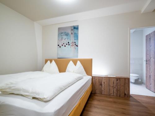 ゴーザウにあるPleasant Apartment in Gosau near Ski Areaのベッドルーム(白い大型ベッド1台、木製ヘッドボード付)