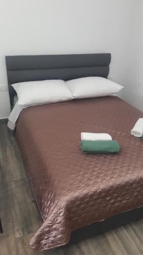 a bed with a brown comforter and a green pillow at Apartman BARAKA in Šibenik