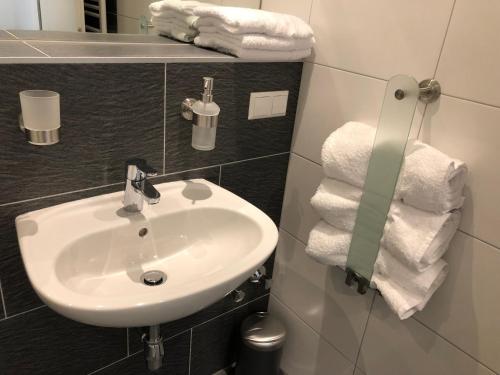 a bathroom with a white sink and towels at KM Hotel Murtal in Knittelfeld