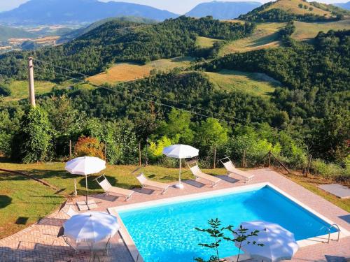 a swimming pool with umbrellas and chairs with a view at Belvilla by OYO Giulio in Acqualagna