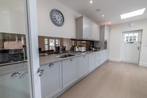 a kitchen with white cabinets and a clock on the wall at Reading Green Park Village Serviced Apartments in Reading