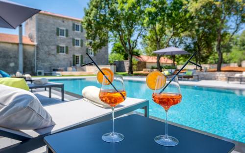 two wine glasses sitting on a table next to a pool at Relais and Wine San Tommaso in Bale