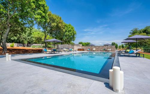 a swimming pool with chairs and umbrellas at Relais and Wine San Tommaso in Bale