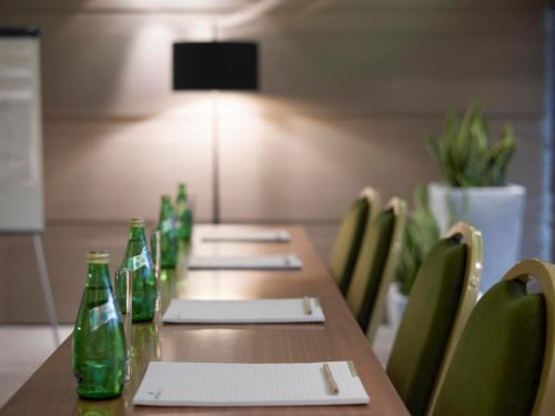 a long wooden table with green bottles and chairs at Anatolia Hotel Komotini in Komotini