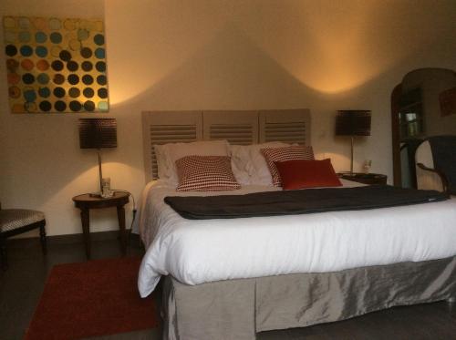 um quarto com uma cama com lençóis brancos e almofadas vermelhas em Chambres d'Hotes Au Val Dormant em Réalville