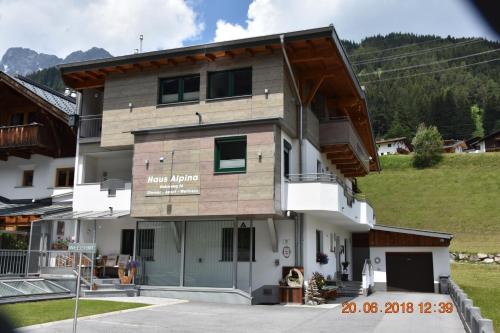 a building with a hill in the background at Gästehaus Alpina in Sankt Anton am Arlberg