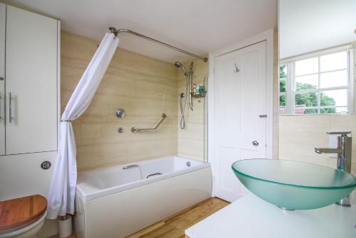 a bathroom with a tub and a glass bowl sink at Stay at Penny's Mill in Frome