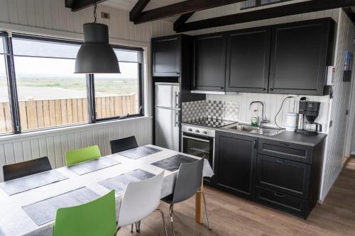 a kitchen with a table and chairs in a kitchen at Black Beach Cottage in Þorlákshöfn