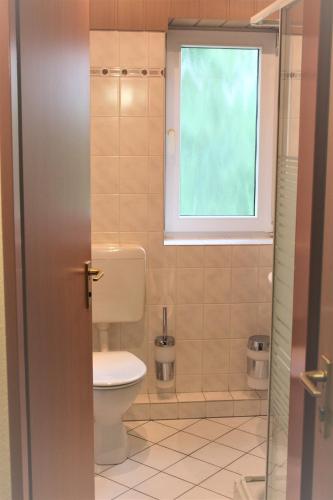 a bathroom with a toilet and a window at Hotel Alsterquelle in Henstedt-Ulzburg
