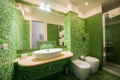 a green tiled bathroom with a sink and a toilet at Malì Trevignano Piccolo Hotel in Trevignano Romano