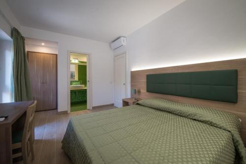 a bedroom with a green bed and a desk and a sink at Malì Trevignano Piccolo Hotel in Trevignano Romano