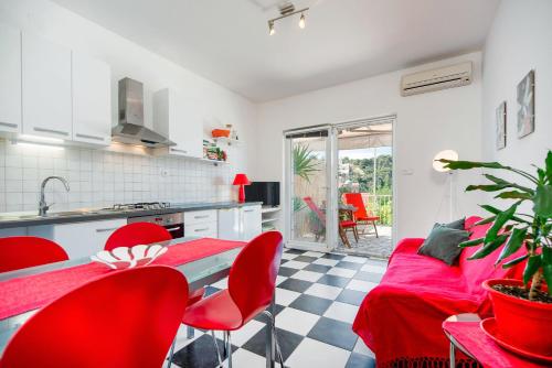 a kitchen and living room with red chairs and a table at Cozy new flat for 2 or 3 in Hvar