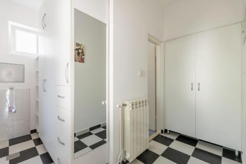a white closet with a mirror and a checkered floor at Cozy new flat for 2 or 3 in Hvar