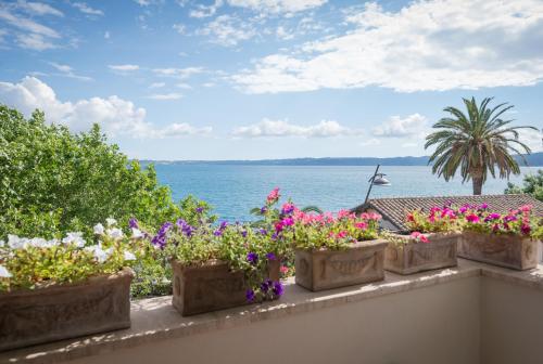 a row of flowers on a balcony overlooking the water at Malì Trevignano Piccolo Hotel in Trevignano Romano