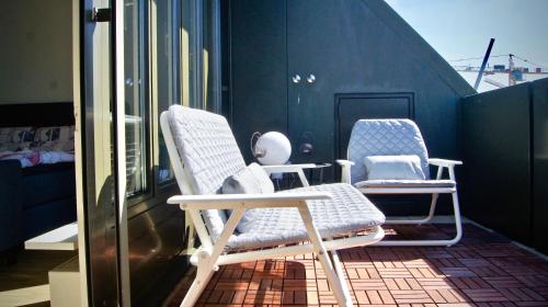 two chairs sitting on top of a balcony at In Swiss Home - Barfüsserplatz BAR street Apartment in Basel