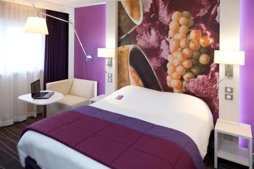 a hotel room with a bed and a purple wall at Mercure Strasbourg Aéroport in Ostwald