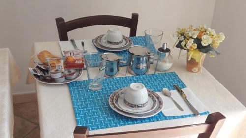 a table with plates and dishes on it with flowers at B&B Oasi Verde in Corvara