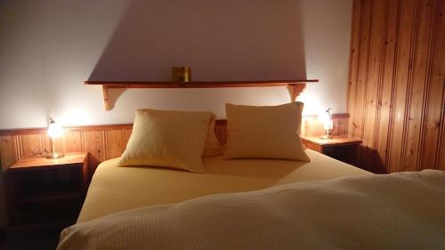 a bedroom with a large white bed with two lamps at Hotel Nufenen in Ulrichen
