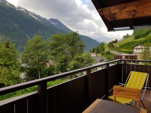 balkon z żółtym krzesłem i widokiem na góry w obiekcie Haus Tannegg w mieście Pettneu am Arlberg