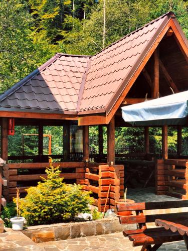a large wooden pavilion with a roof and benches at Pensiunea Flora in Cîrţişoara