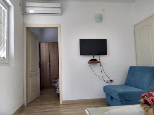 a living room with a blue chair and a tv on the wall at Apartment Djokic in Sutomore