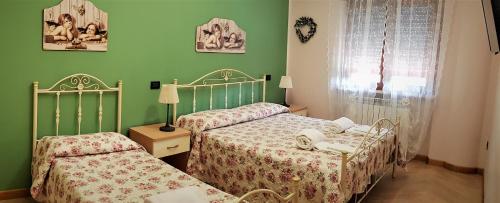 two beds in a bedroom with green walls at Glamour Bed & Breakfast in Montalto Uffugo