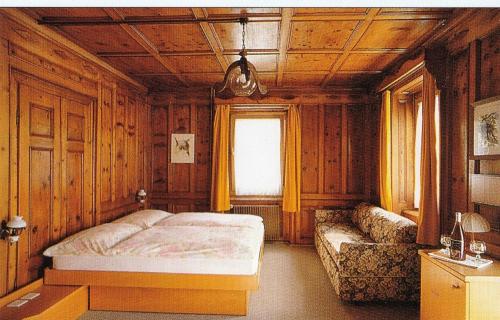 1 dormitorio con cama y sofá en Hotel Rätia, en Tiefencastel