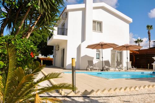 ein weißes Haus mit einem Pool und 2 Sonnenschirmen in der Unterkunft Villa Olivia, Coral Bay in Coral Bay