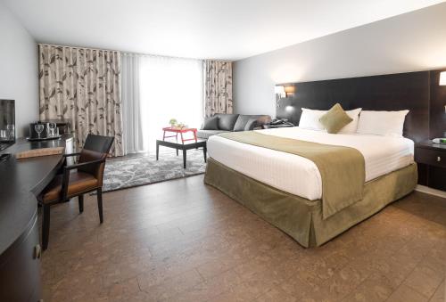ein Hotelzimmer mit einem großen Bett und einem Schreibtisch in der Unterkunft Auberge des Gallant in Rigaud