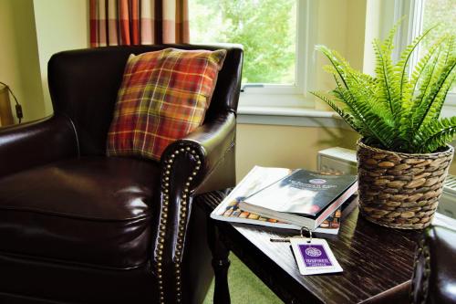 a black leather chair and a table with a plant at Bridge of Cally Hotel in Blairgowrie