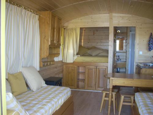 a room with a bed and a desk in a cabin at Les Roulottes de la Ferme des Chanaux in Saint-Julien-dʼAnce