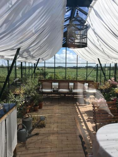 eine Terrasse mit Bänken unter einem weißen Zelt in der Unterkunft Rosengave in Alsted