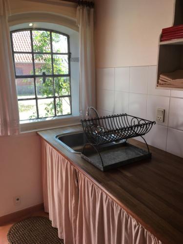 eine Küchentheke mit einem Waschbecken und einem Fenster in der Unterkunft Rosengave in Alsted