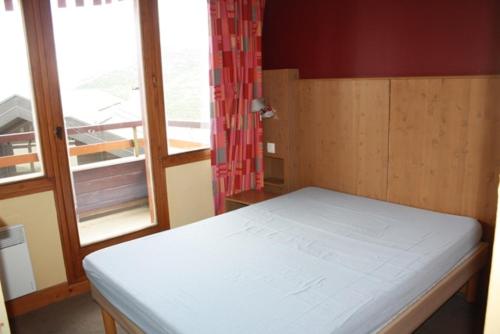 a small bedroom with a bed and a window at L'ours blanc in LʼHuez