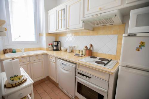 La cuisine est équipée de placards blancs et d'un four avec plaques de cuisson blanches. dans l'établissement Bohemian Apartment by Connexion, à Cannes