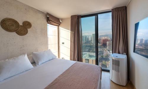 um quarto com uma cama branca e uma grande janela em Zip Housing El Golf em Santiago