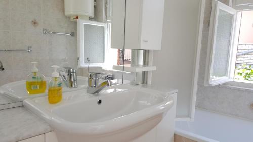 uma casa de banho branca com um lavatório e um espelho em Guest House Izola em Izola