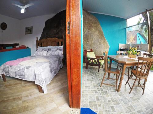 a bedroom with a bed and a table and chairs at Suítes Cantinho da Pedra in Abraão