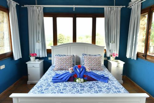 a bedroom with a bed with blue walls and windows at Mas Valoria in Peratallada